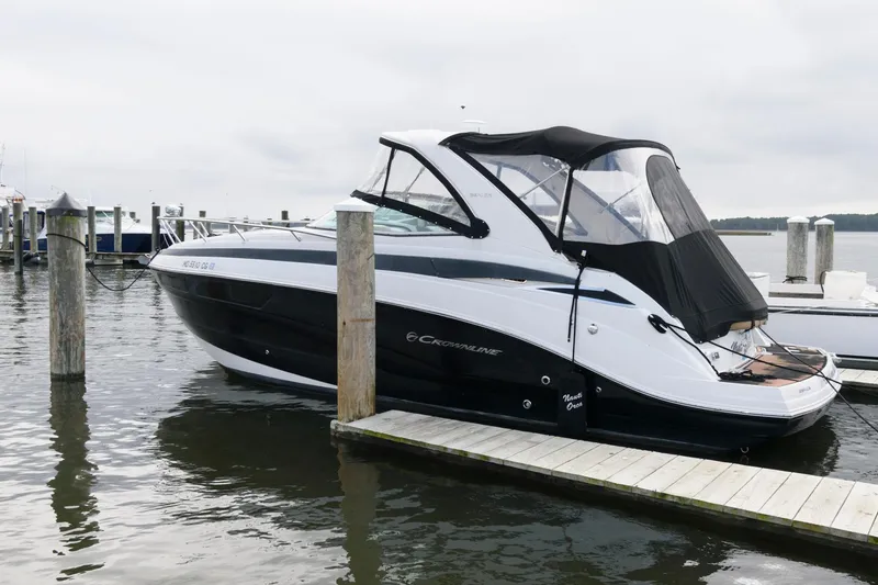 The Image of 2014 Crownline 294 CR boat docked at marina, featuring sleek black and white design. - 0