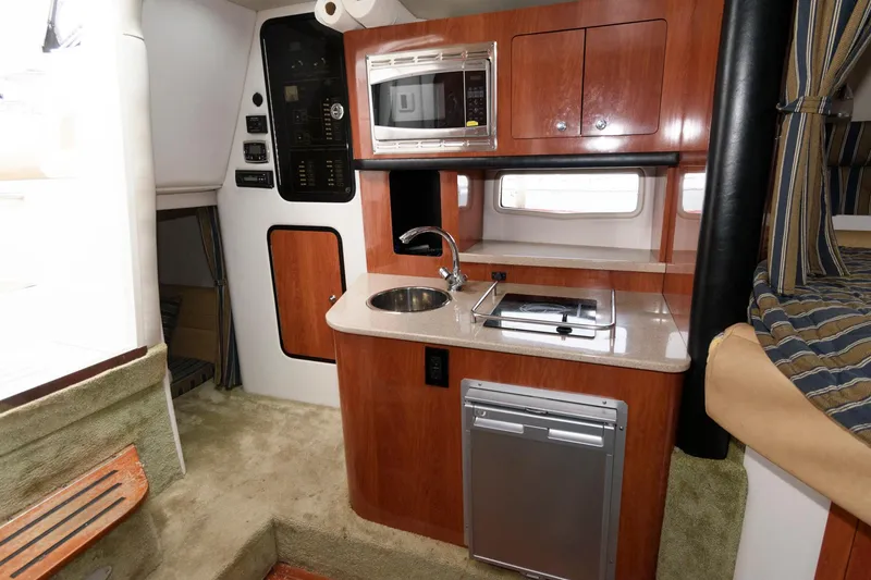 Slide: The Image of 2014 Crownline 294 CR boat interior with kitchenette, featuring microwave, sink, and compact fridge. - 17