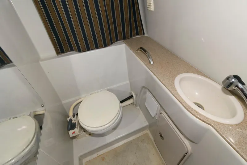 Slide: The Image of 2014 Crownline 294 CR boat bathroom with toilet, sink, and striped curtain. - 20