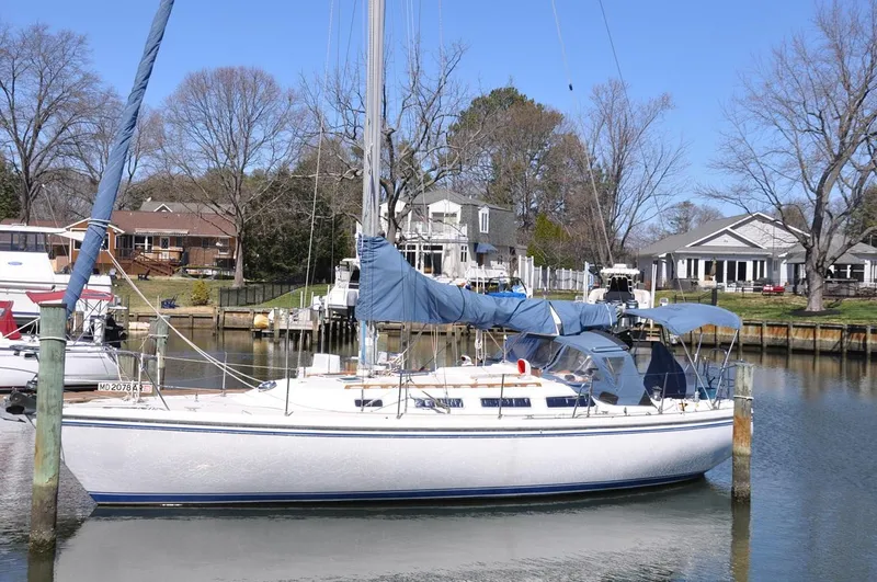 Slide: The Image of 1987 Catalina 36 Tall Rig sailboat docked in a serene residential marina. - 1