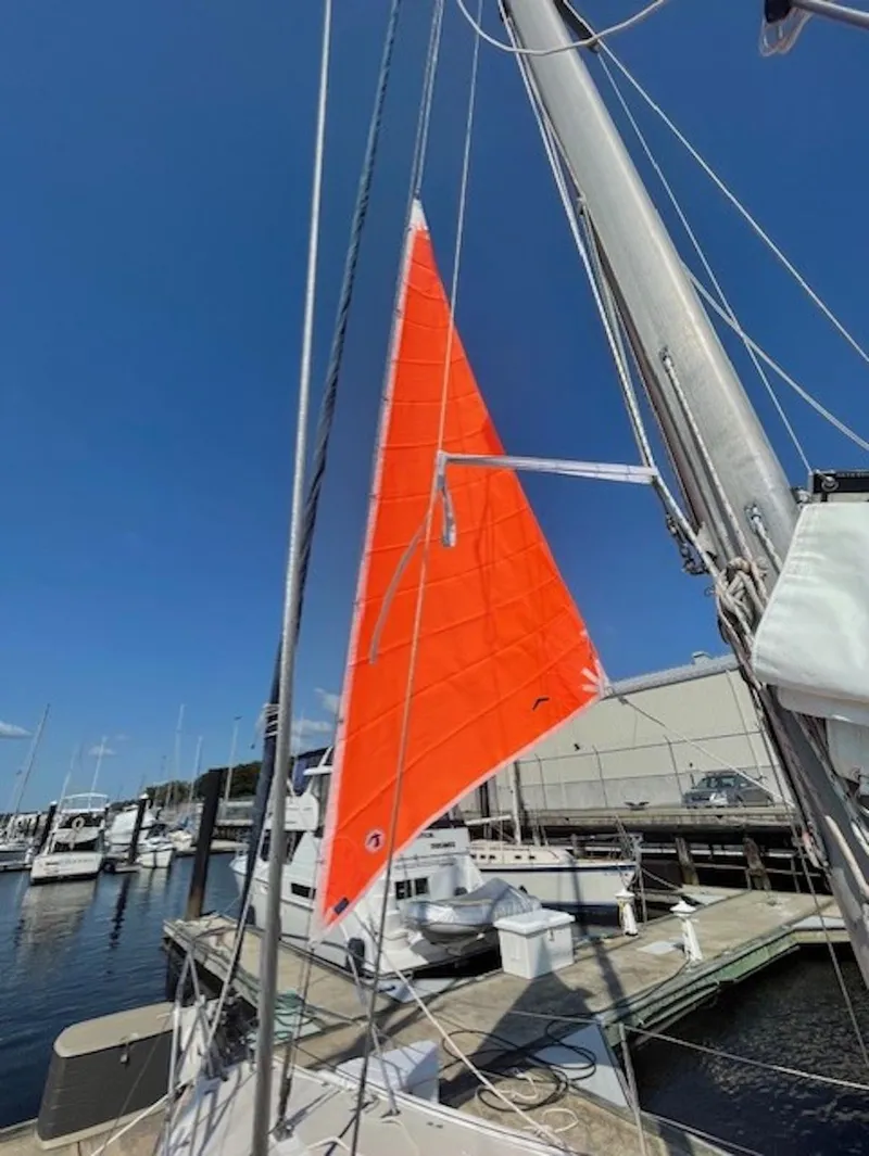 Slide: The Image of 1987 Catalina 36 Tall Rig sailboat with bright orange sail at marina. - 18