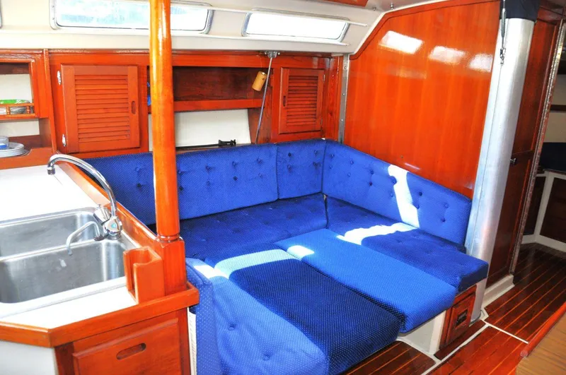 Slide: The Image of Interior of 1987 Catalina 36 Tall Rig sailboat with blue cushioned seating and wooden cabinetry. - 20