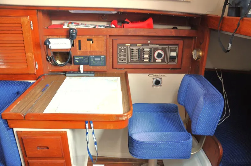Slide: The Image of Navigation station inside a 1987 Catalina 36 Tall Rig sailboat, featuring blue seating and control panel. - 22