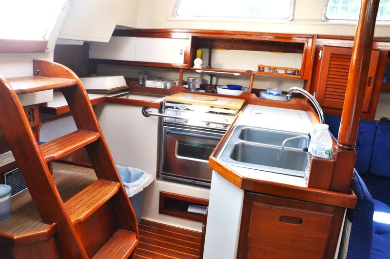 Slide: The Image of 1987 Catalina 36 Tall Rig yacht interior with wooden cabinetry, kitchen sink, and stove. - 23