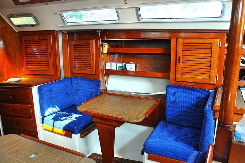 Slide: The Image of Interior of 1987 Catalina 36 Tall Rig sailboat with blue cushioned seating and wooden cabinetry. - 25