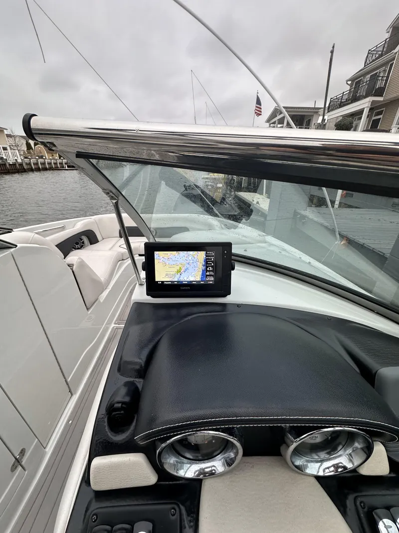 Slide: The Image of 2018 Crownline Eclipse E24 XS boat dashboard with navigation system, docked by waterfront homes. - 5