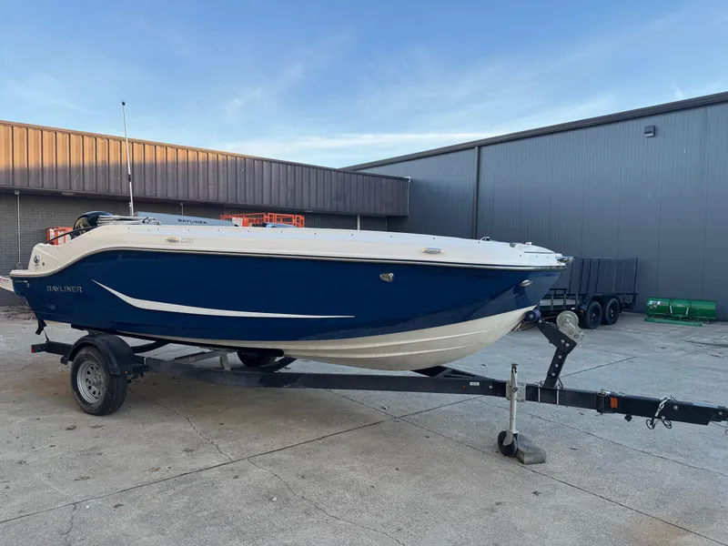 Slide: The Image of 2025 Bayliner D20 boat on trailer, parked outdoors near industrial building. - 0
