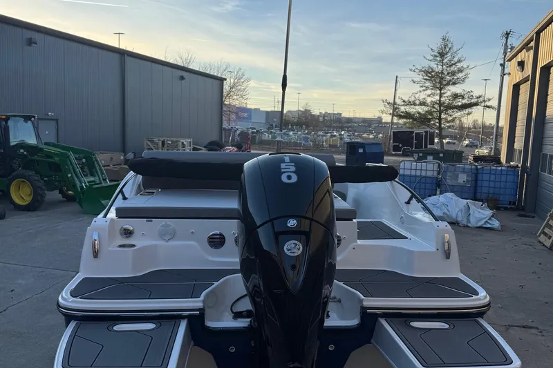 Slide: The Image of 2025 Bayliner D20 boat with outboard motor, parked outdoors near industrial buildings. - 7