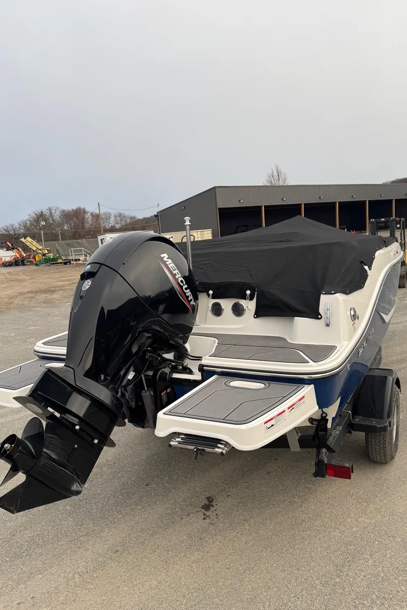Slide: The Image of 2025 Bayliner D20 boat with Mercury outboard motor, covered and parked outdoors. - 9