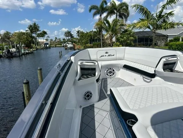 Slide: The Image of 2024 Nor-Tech 390 Sport boat with luxurious seating, docked by a scenic waterway. - 29