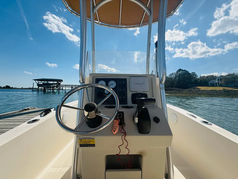 Slide: The Image of 2015 Pioneer 180 Islander boat dashboard with steering wheel, docked by a scenic waterfront. - 11