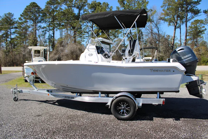Slide: The Image of 2025 Tidewater 198 CC Adventure boat on trailer, parked outdoors with trees in background. - 2