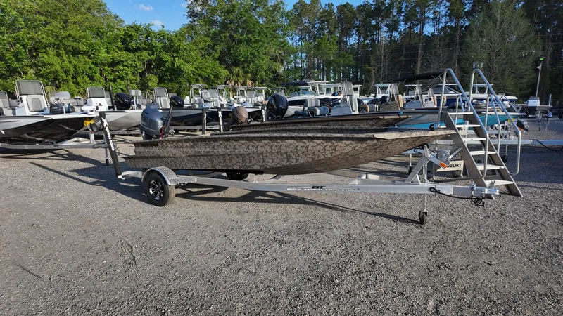Slide: The Image of 2025 Xpress H18DB boat on trailer in outdoor lot with trees in background. - 10