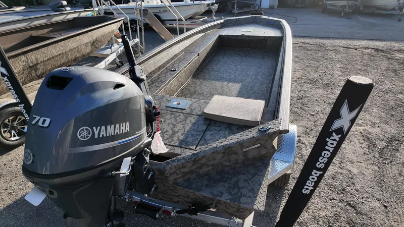 Slide: The Image of 2025 Xpress H18DB boat with Yamaha 70 engine, parked on gravel. - 20