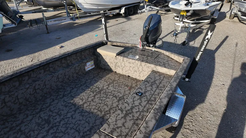 Slide: The Image of 2025 Xpress H18DB boat with camouflage interior and outboard motor in a marina setting. - 28