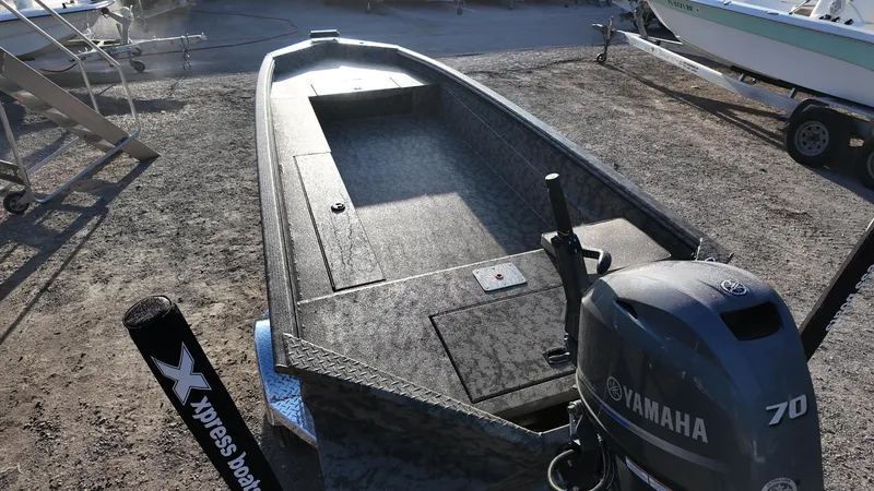 Slide: The Image of 2025 Xpress H18DB boat with Yamaha 70 engine, parked on gravel. - 29