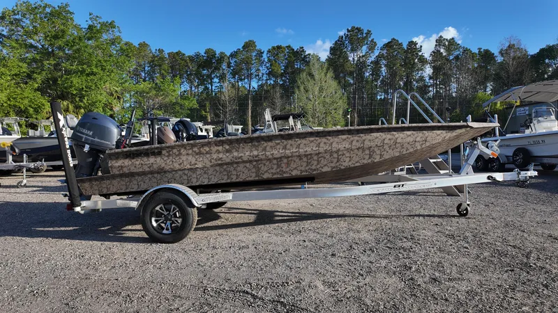 Slide: The Image of 2025 Xpress H18DB boat on trailer in outdoor lot, surrounded by trees and other boats. - 4