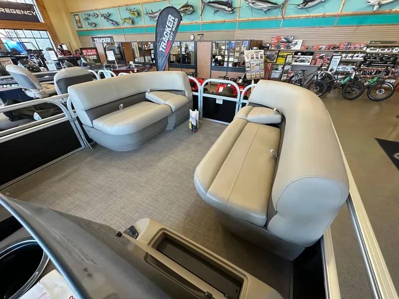 Slide: The Image of 2025 Sun Tracker Party Barge 16 DLX interior with plush seating in showroom. - 2