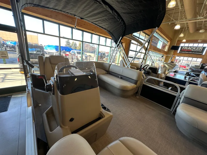 Slide: The Image of 2025 Sun Tracker Party Barge 16 DLX interior with seating and helm, displayed indoors. - 3
