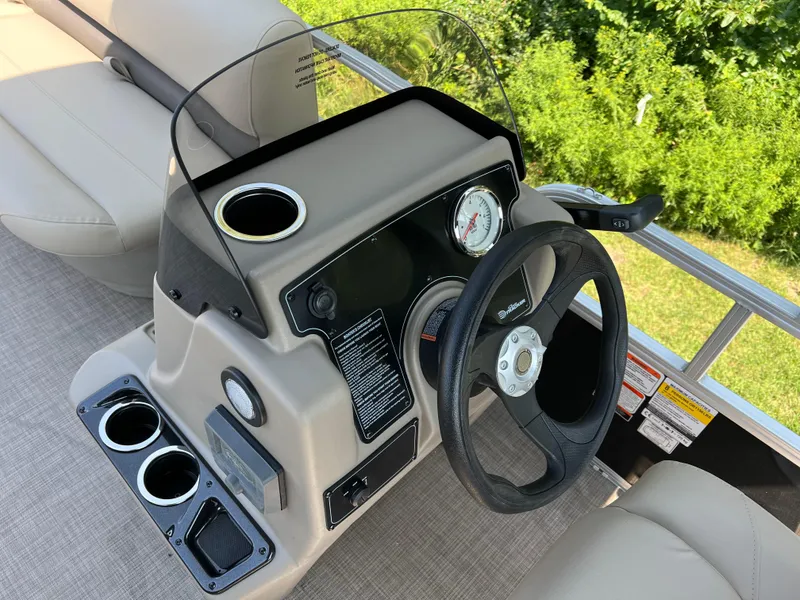 Slide: The Image of 2025 Sun Tracker Party Barge 16 DLX steering console with cup holders and gauges. - 8