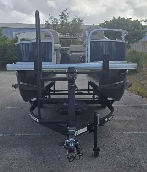 Slide: The Image of 2025 Sun Tracker Bass Buggy 16 XL Select pontoon boat on trailer, parked outdoors. - 4