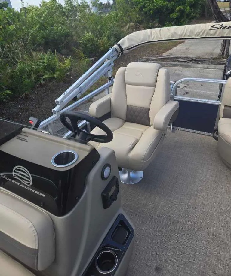 Slide: The Image of 2025 Sun Tracker Bass Buggy 16 XL Select interior with beige seating and steering console. - 8