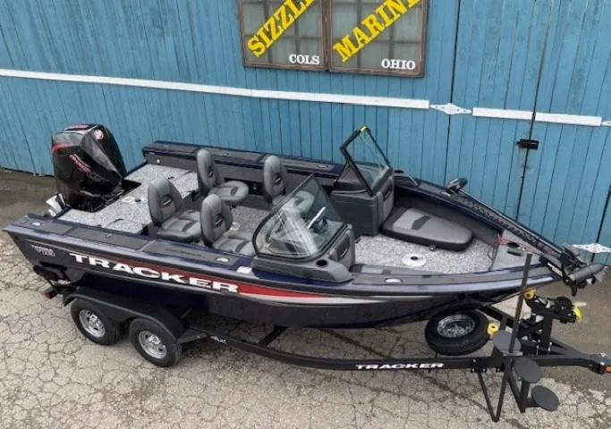 Slide: The Image of 2025 Tracker Targa V-18 Combo boat on trailer, parked outside blue building. - 3