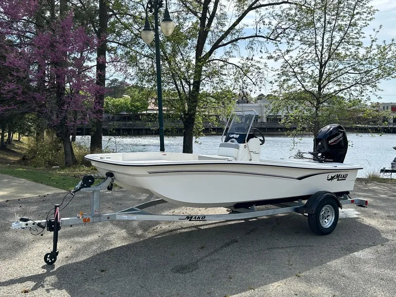 Slide: The Image of 2025 Mako Pro Skiff 15 CC boat on trailer by a scenic lakeside. - 0