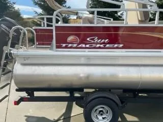 Slide: The Image of 2025 Sun Tracker Bass Buggy 18 DLX pontoon boat on trailer, side view. - 2