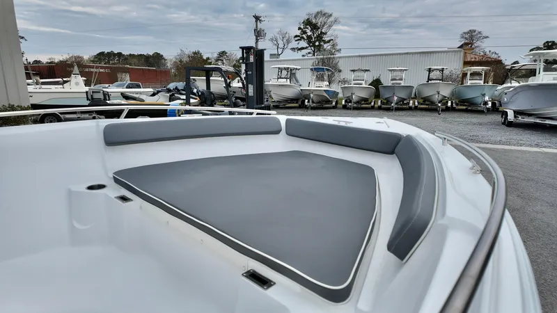 Slide: The Image of 2025 ALK2 Powerboats 22CRX bow seating area with gray cushions, docked among other boats. - 7