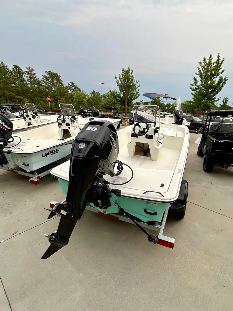 Slide: The Image of 2025 Mako Pro Skiff 15 CC boat with outboard motor, parked outdoors. - 2