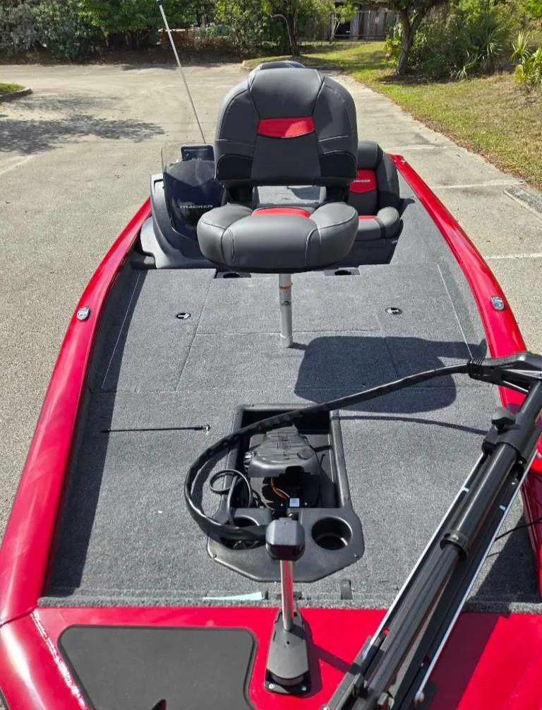 Slide: The Image of 2025 Tracker Pro Team 175 boat with red exterior and gray seating, parked outdoors. - 5