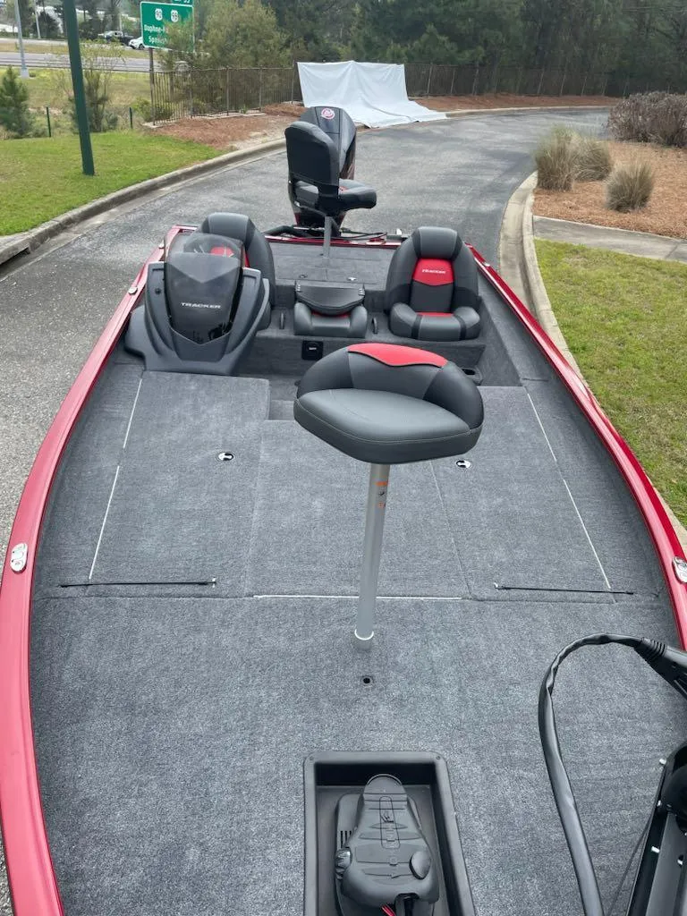 Slide: The Image of 2025 Tracker Savage 215 boat with red accents and seating on a paved path. - 3
