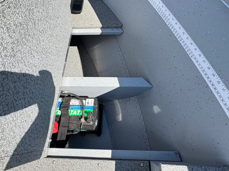 Slide: The Image of 2021 Lund 1600 Fury Tiller boat interior with battery and measuring ruler. - 11