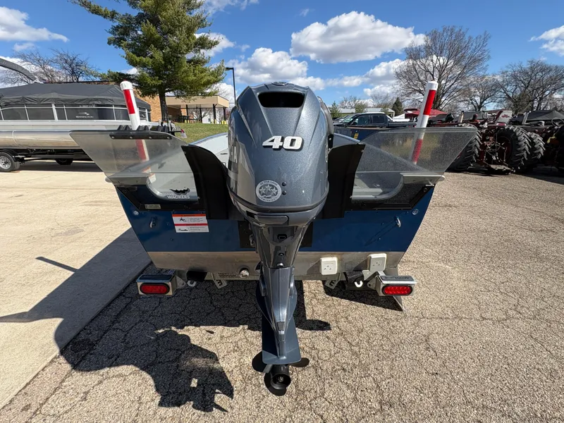 Slide: The Image of 2021 Lund 1600 Fury Tiller boat with 40 HP motor, parked outdoors. - 2