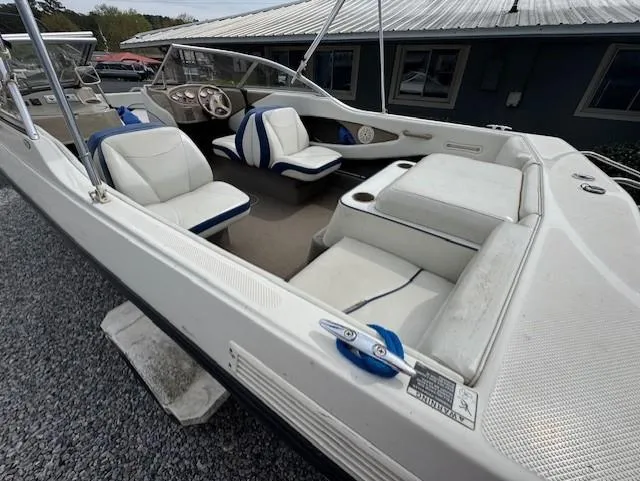 Slide: The Image of 2005 Bayliner 195 Bowrider boat with white and blue seating, parked on gravel. - 3