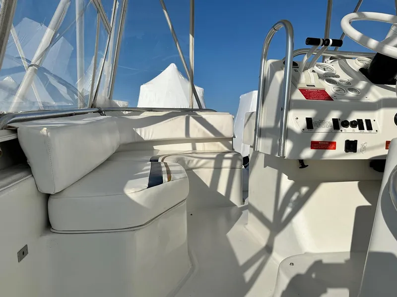 Slide: The Image of 1996 Mainship 40 Sedan Bridge helm with white seating and control panel under clear blue sky. - 12