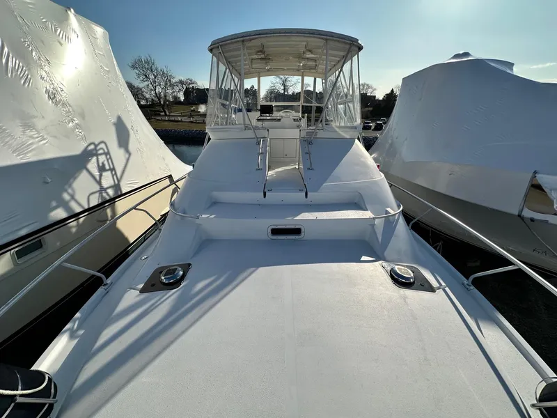 Slide: The Image of 1996 Mainship 40 Sedan Bridge yacht docked, featuring a spacious deck and covered helm. - 25