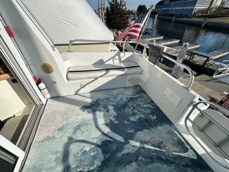 Slide: The Image of 1996 Mainship 40 Sedan Bridge deck with seating, American flag, and waterfront view. - 31