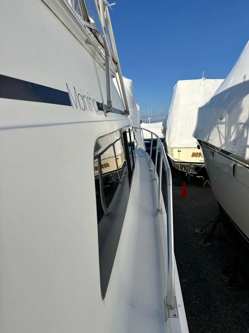 Slide: The Image of 1996 Mainship 40 Sedan Bridge yacht docked, side view with clear blue sky. - 32