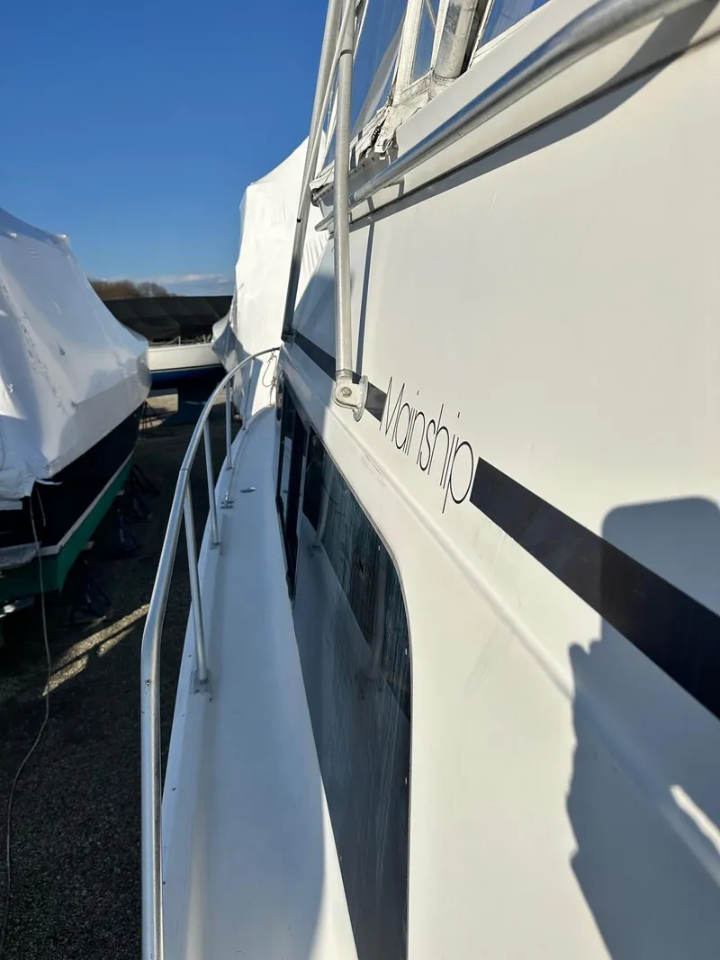 Slide: The Image of 1996 Mainship 40 Sedan Bridge boat side view, docked under clear blue sky. - 33