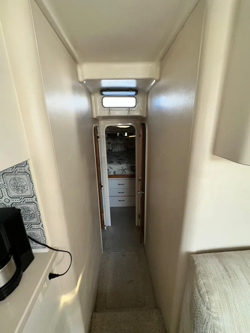 Slide: The Image of Narrow hallway inside 1996 Mainship 40 Sedan Bridge, leading to a cozy cabin area. - 49