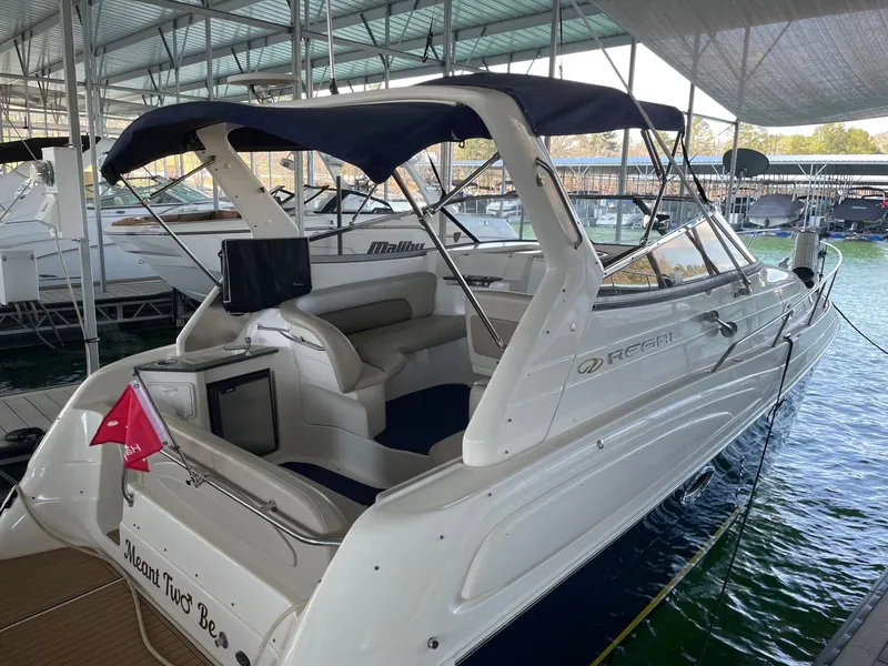 Slide: The Image of 2005 Regal 2860 Express Cruiser docked under a canopy, featuring a spacious seating area. - 0