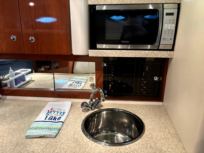 Slide: The Image of 2005 Regal 2860 Express Cruiser kitchen with sink, microwave, and wooden cabinets. - 14