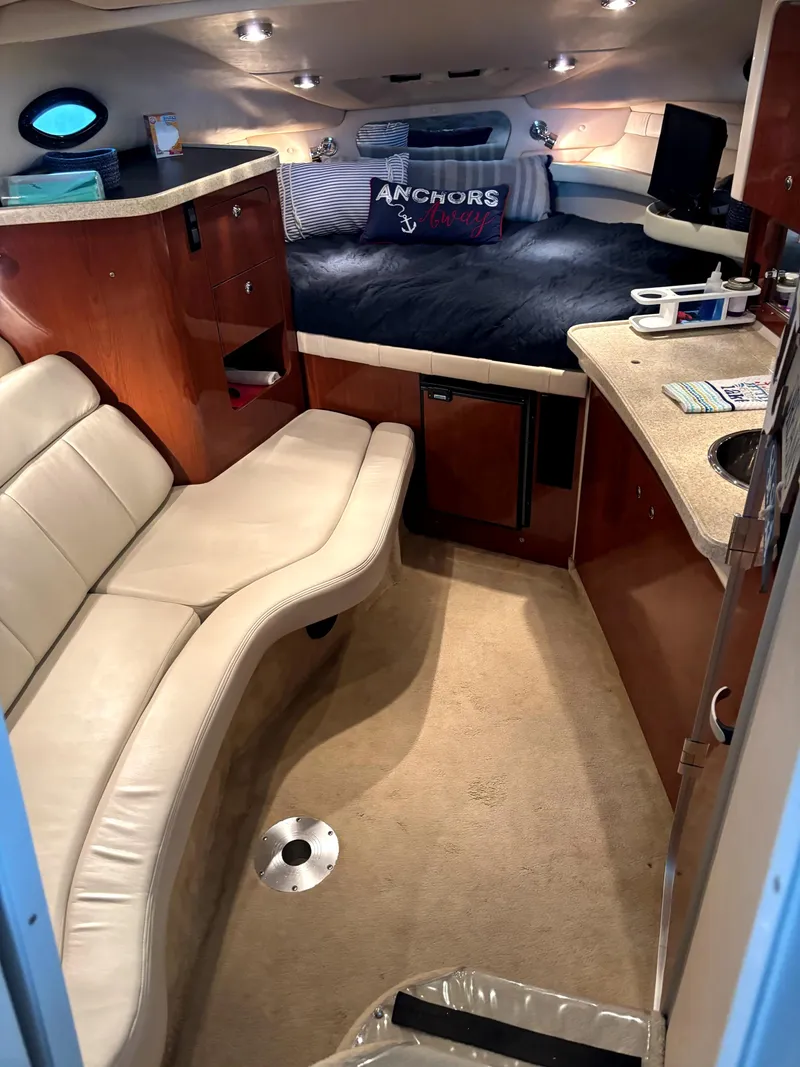 Slide: The Image of 2005 Regal 2860 Express Cruiser interior with seating, kitchenette, and cozy sleeping area. - 21