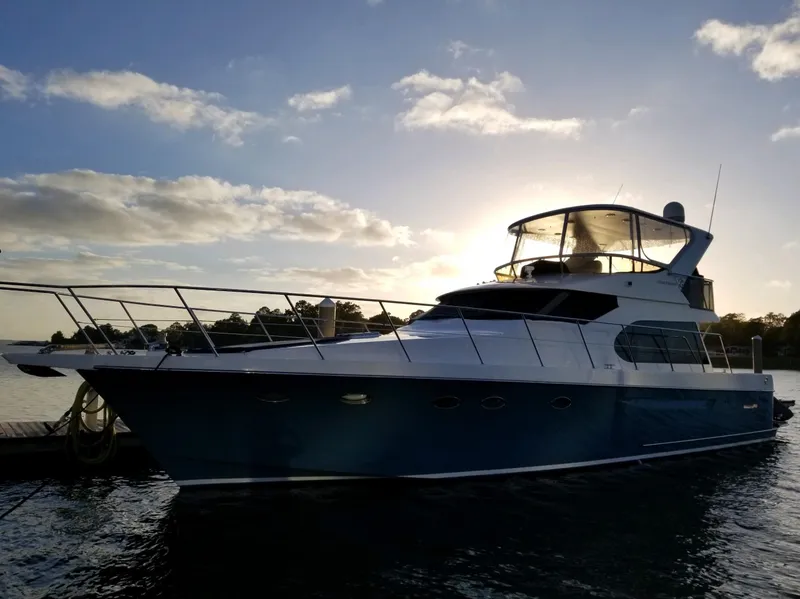 Slide: The Image of 2005 Ocean Alexander 52 Sedan yacht docked at sunset, silhouetted against a vibrant sky. - 2