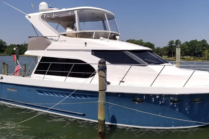 Slide: The Image of 2005 Ocean Alexander 52 Sedan yacht docked in a marina, featuring a sleek blue and white design. - 28