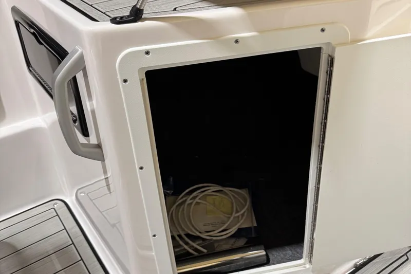 Slide: The Image of 2024 Yamaha Boats 195S storage compartment with open door, showing interior space and coiled cables. - 13