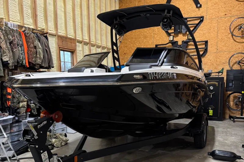 Slide: The Image of 2024 Yamaha Boats 195S in a garage, black exterior, on a trailer. - 2