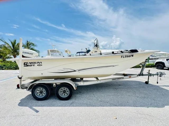 Slide: The Image of 2015 Carolina Skiff 198DLX boat on trailer, parked outdoors under a clear sky. - 17
